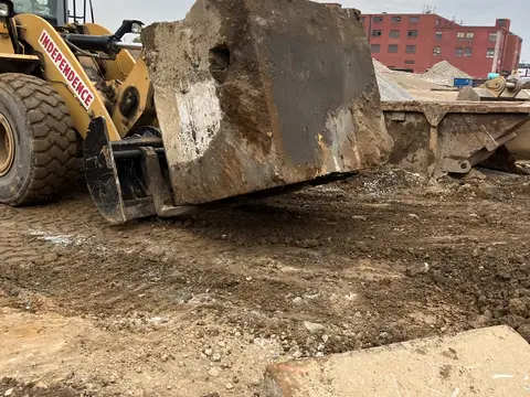 Loader moving a concrete slab. Site work, August 2026
