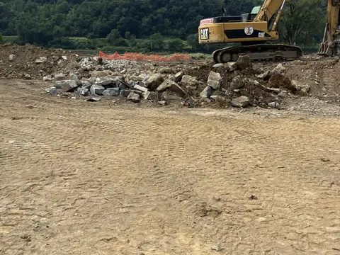 Excavator working the north end of the site. Site work, August 2026