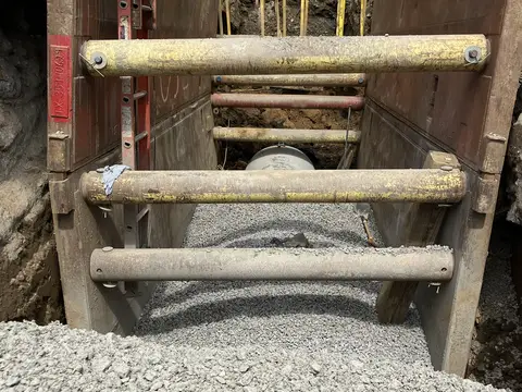 Trench box in a utility excavation. Site work, August 2026
