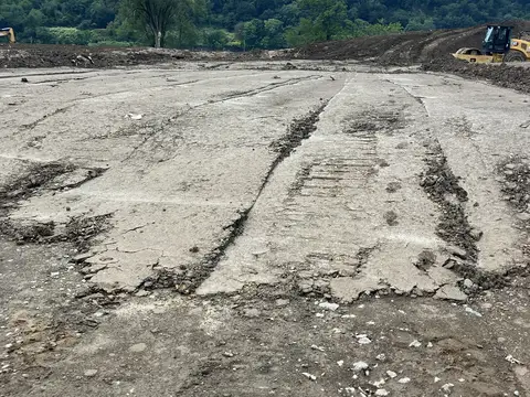 Graded ground along the riverfront. Site work, August 2026