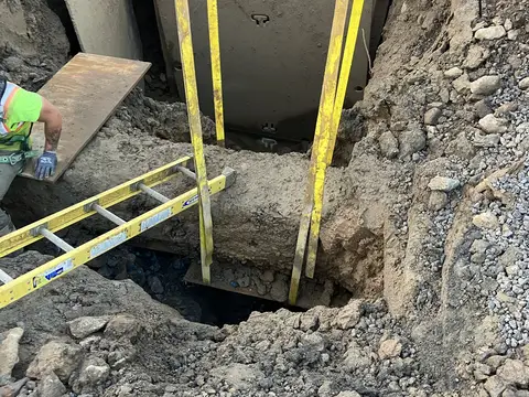 Shoring and ladder access to a utility trench. Site work, August 2026