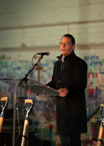 Groundbreaking ceremony speaker at the podium, flanked by ceremonial shovels